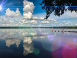 Fototapeta Fototapety pomosty - summer landscape of clouds reflecting in the lake water with sun and jetty