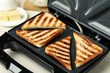 © New Africa - Modern sandwich maker with bread slices on white table, closeup