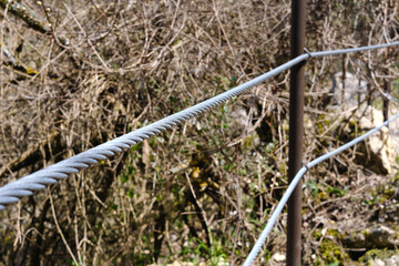 Interlocking steel cable secures a barrier on a mountain path.