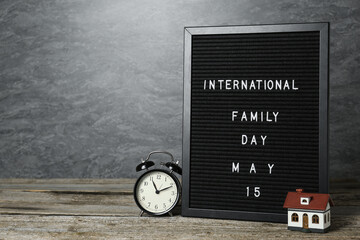 Happy Family Day. Black letter board with text, clock and house model on wooden table. Space for design