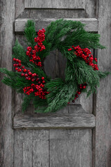 Poster - Beautiful Christmas wreath with red berries hanging on wooden wall