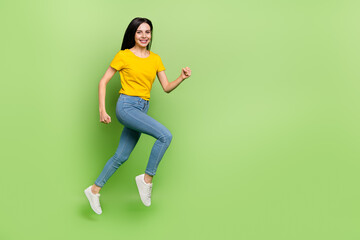 Wall Mural - Full body profile photo of excited cheerful girl rush fast empty space isolated on green color background