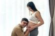 © tonefotografia - Young pregnant woman with husband embracing and expecting a baby at home