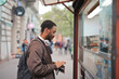 © olly - young man buys some bread in a kiosk