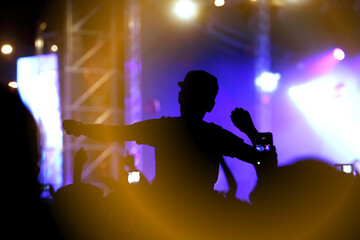 Wall Mural - Viewers under the stage. The man with raised hands during summer festival rock concert.