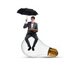 © adam121 - A young businessman sits on a light bulb