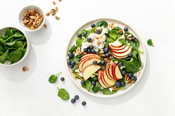 Wall Mural - Apple and spinach fresh sweet fruit salad with blueberry, cheese cottage and walnuts, top view