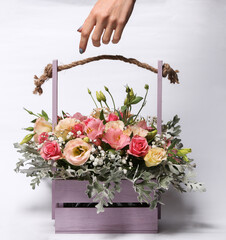 Sticker - Beautiful bouquet of different flowers in a wooden basket and wooden hand isolated on a white background.