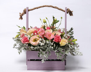 Sticker - Beautiful bouquet of different flowers in a wooden basket isolated on a white background.