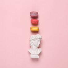 Bust Of David With French Macaroons On Pink Pastel Background. Minimal Flat Lay Style Still Life. Food Concept