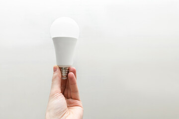 Energy-saving light bulb in male hand close-up against the background of a concrete wall