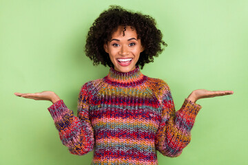 Wall Mural - Portrait of cheerful amazed lady hands palms hold demonstrate empty space isolated on green color background