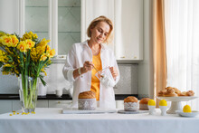 A Woman In The Kitchen Decorates Easter Pastries.