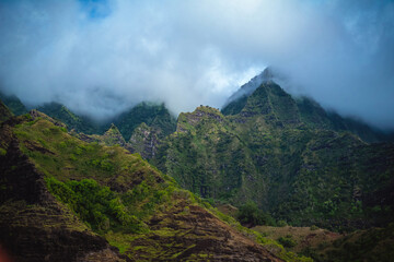  The gorgeous rugged wilderness and cliffs of Kauai's Napali Coast in Hawaii, with low clouds and mist hanging over the mountain peaks under a stormy grey sky