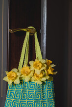 Bright Crochet Bag With Yellow Daffodils Hanging On Door Handle. Blue Yellow Handmade Bag For Shopping With Geometric Pattern. Zero Waste Concept.