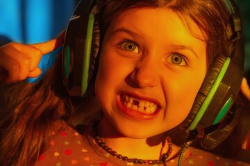 aggressive uncontrollable child shows teeth, emotional girl in headphones on a blue background in neon colored light, close-up