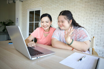 down syndrome teenage girl and her teacher studying how to use laptop computer and talking online to someone