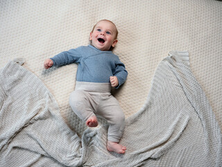 Wall Mural - funny baby newborn baby smiling lies on his back on the bed