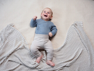 Wall Mural - funny baby newborn baby smiling lies on his back on the bed