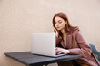 © LIGHTFIELD STUDIOS - young woman with red hair using laptop outside.