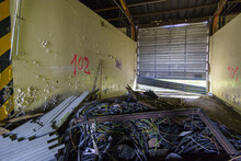 Inside Of An Abandoned Industrial Building With Metal Garage Gate And Many Electrical Wires On The Ground