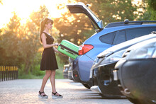 Young Female Driver Loading Luggage Suitcase Bag Inside Her Car. Travelling And Vacations Concept