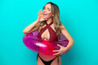 Woman in swimsuit holding floater isolated on blue background whispering something