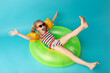 © яна винникова - Happy little child girl in a swimwear suit lying on a bright inflatable circle. Blue background. Top view. Summer and vacation concept