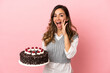 © luismolinero - Young woman holding birthday cake over isolated pink background shouting with mouth wide open