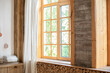 © stock_studio - Big wooden window with frame and window sill and nature on background. Empty room, wooden window with with White linen curtain and logs decoration wall on a sunny day indoor shot. Scandinavian room