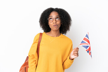 Wall Mural - Young African American woman holding an United Kingdom flag isolated on white background and looking up