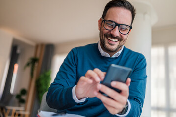 Close-up of smiling male entrepreneur networking on smart phone at office