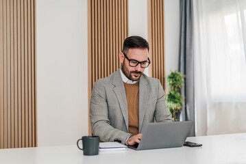 Confident businessman working on laptop while sitting at office desk