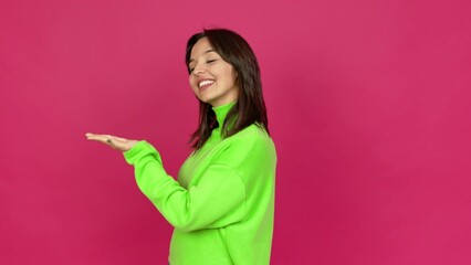 Wall Mural - Young brunette woman extending hands to the side and inviting to come over isolated background