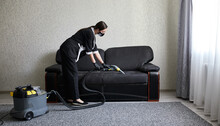 Cleaning Service Company Employee Removing Dirt From Furniture In Flat With Professional Equipment. Female Housekeeper Arm Cleaning Sofa With Washing Vacuum Cleaner