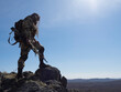 The concept of modern warfare - a sniper mercenary inspects the area from a high mountain.