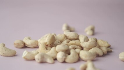 Poster - slow motion of cashew nuts falling on light pink background 