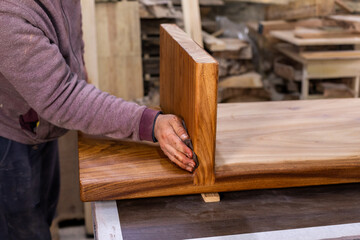 Closeup of carpenter coating a wooden table with protective flaxseed oil