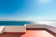 White terrace with red floor and sea view on a sunny day.