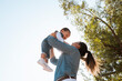 © alejandro - young mother lifts her son in her arms in the park at sunset - low angle