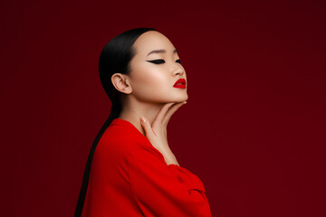 Asian beauty fashion portrait. Profile view of korean young girl with  makec up posing against red background