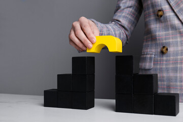 Businesswoman building bridge with colorful blocks at table, closeup. Connection, relationships and deal concept