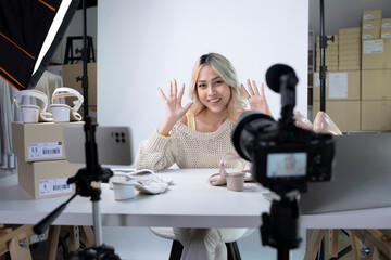 Young attractive Asian female blogger or vlogger looking at camera saying hello. Modern businesswoman using social media for marketing. Business online influencer on social media concept.