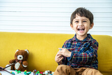 Handsome Mixed Race Boy, Playing In The Living Room In The House, Playing With Plasticine Statue, Happy Child, Little Kid Play With Toys At Home, He Is Wearing A Long Sleeve Shirt