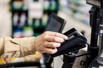 Close up of a man using phone app for payment at supermarket.