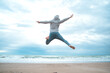 Feel good and freedom concept. Copy space of happy man jumping on beach. 
