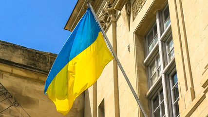 Wall Mural - The Ukraine flag at the window waving in the wind. In support of the conflict of Ukraine against the Russia.