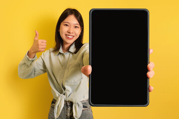 Poster - Young Asian woman showing tablet with empty screen, gesturing thumb up, offering mockup for website or application