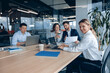 © Yaroslav Astakhov - confident smiling businesswoman sitting at the office with group of colleagues, on background.