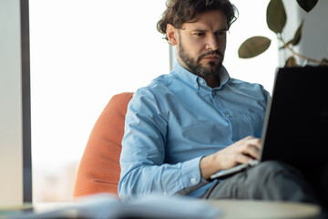 Aufkleber - Businessman using laptop sitting on bean bag in office